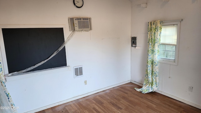 spare room featuring hardwood / wood-style floors and an AC wall unit