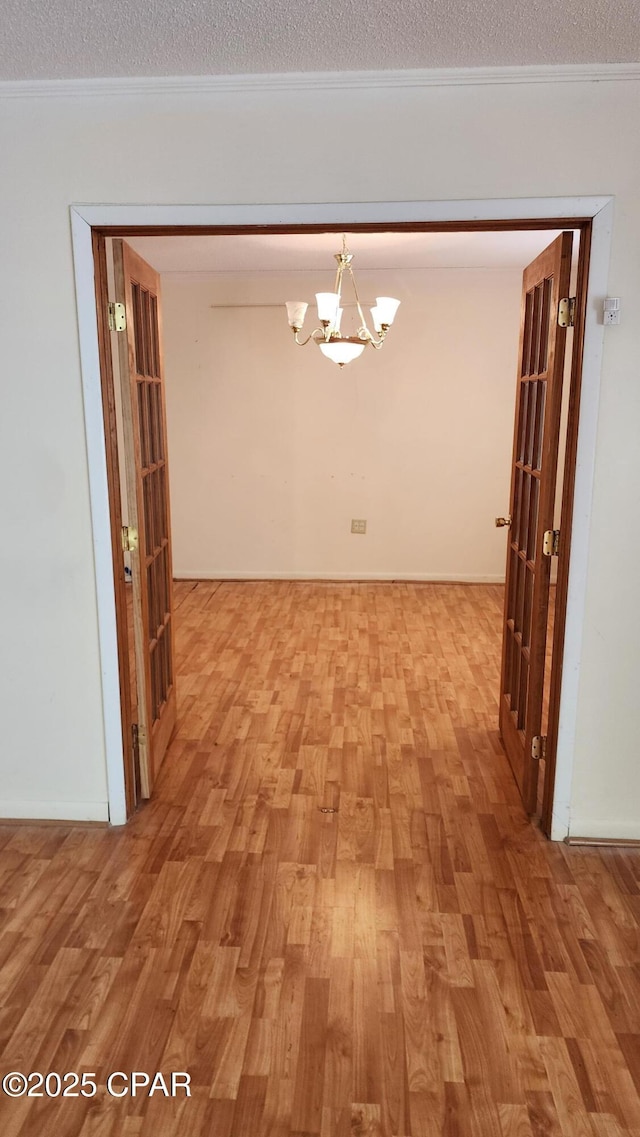 hall featuring crown molding, wood-type flooring, a chandelier, and a textured ceiling