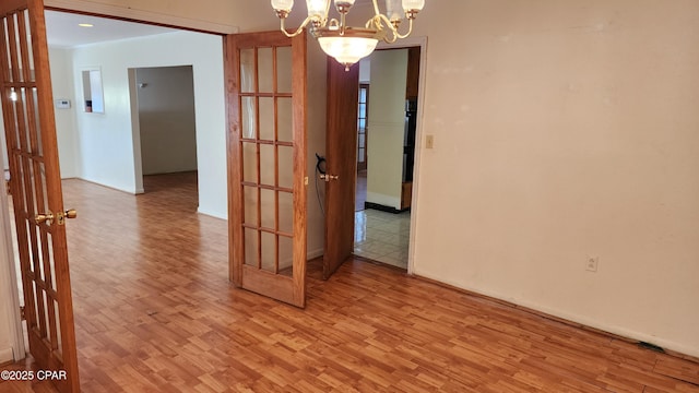 empty room with an inviting chandelier and light hardwood / wood-style flooring