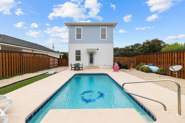 rear view of property featuring a fenced in pool and a patio