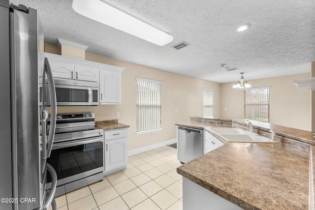 kitchen with light tile patterned floors, sink, white cabinetry, stainless steel appliances, and a textured ceiling