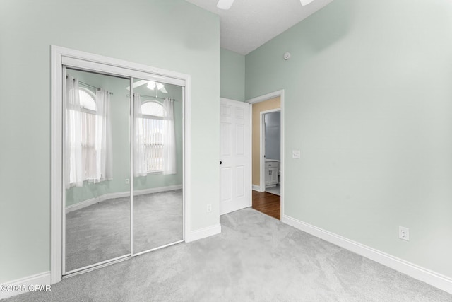 unfurnished bedroom with light carpet, a closet, and ceiling fan