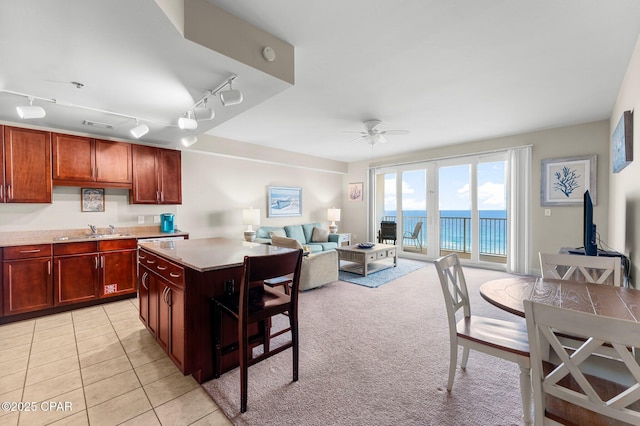 kitchen featuring rail lighting, sink, a center island, light tile patterned floors, and ceiling fan