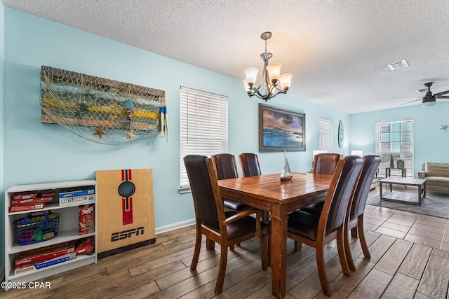 dining space with ceiling fan with notable chandelier and a textured ceiling