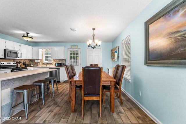17214 Front Beach Rd Unit T28, Panama City Beach, FL 32413 - dining area with a chandelier, dark wood-style floors, and baseboards
