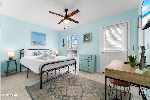 bedroom with a textured ceiling, ceiling fan, and light hardwood / wood-style floors