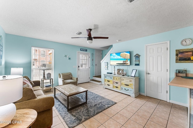 living room featuring ceiling fan, light tile patterned floors, and a textured ceiling