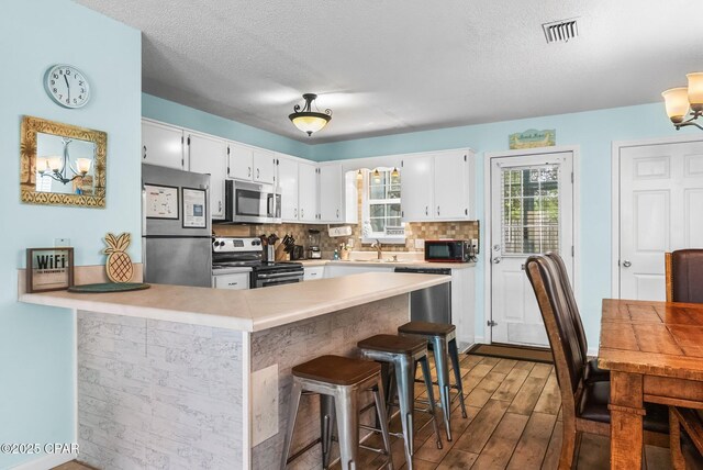 17214 Front Beach Rd Unit T28, Panama City Beach, FL 32413 - kitchen featuring appliances with stainless steel finishes, dark wood-type flooring, a peninsula, a sink, and white cabinetry