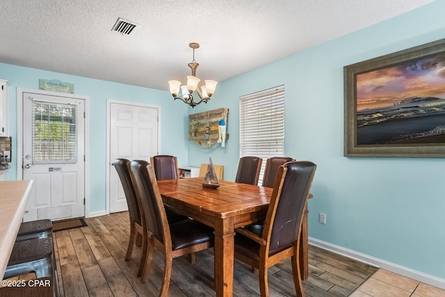 dining space featuring a chandelier, a textured ceiling, and light hardwood / wood-style flooring