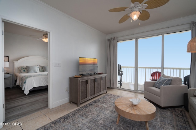 living room featuring light tile patterned flooring, ornamental molding, and ceiling fan