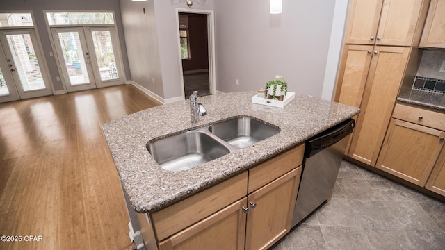 kitchen featuring dishwasher, sink, light stone countertops, a center island with sink, and french doors