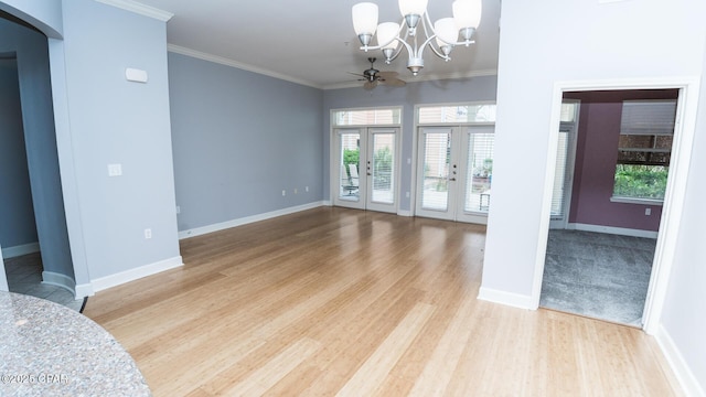 spare room featuring french doors, crown molding, ceiling fan with notable chandelier, and light hardwood / wood-style flooring