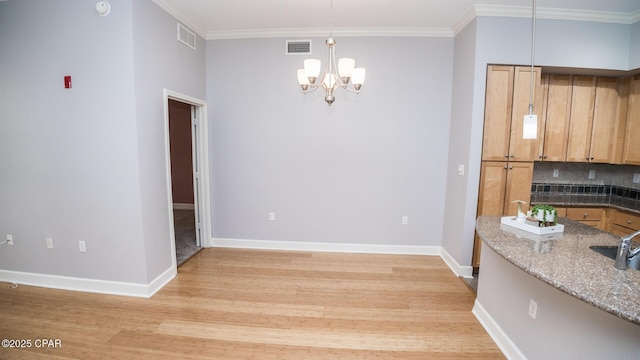 unfurnished dining area with crown molding, an inviting chandelier, and light hardwood / wood-style floors