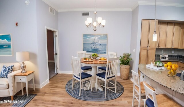 dining area with an inviting chandelier, ornamental molding, and light wood-type flooring