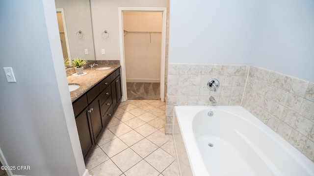 bathroom with tiled tub, vanity, and tile patterned floors