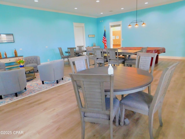 dining space with crown molding and light wood-type flooring