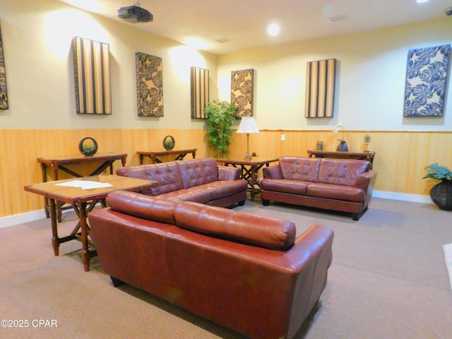 carpeted living room featuring wood walls