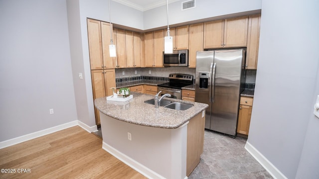 kitchen with sink, light stone counters, hanging light fixtures, appliances with stainless steel finishes, and backsplash