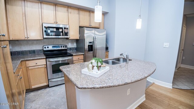 kitchen featuring sink, pendant lighting, stainless steel appliances, a kitchen island with sink, and backsplash