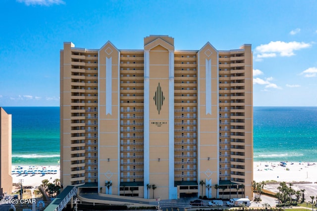 view of building exterior with a beach view and a water view