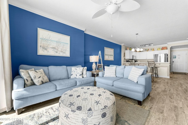 living room featuring crown molding, hardwood / wood-style flooring, and ceiling fan with notable chandelier