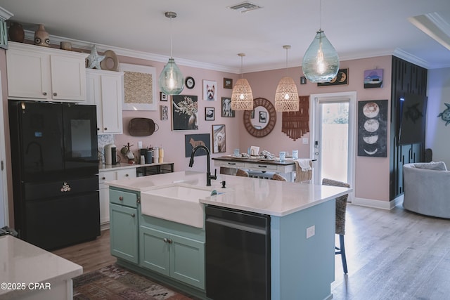 kitchen with sink, a center island with sink, white cabinets, and decorative light fixtures