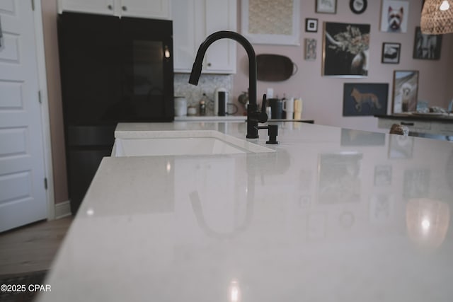 interior details with sink, backsplash, and hardwood / wood-style flooring