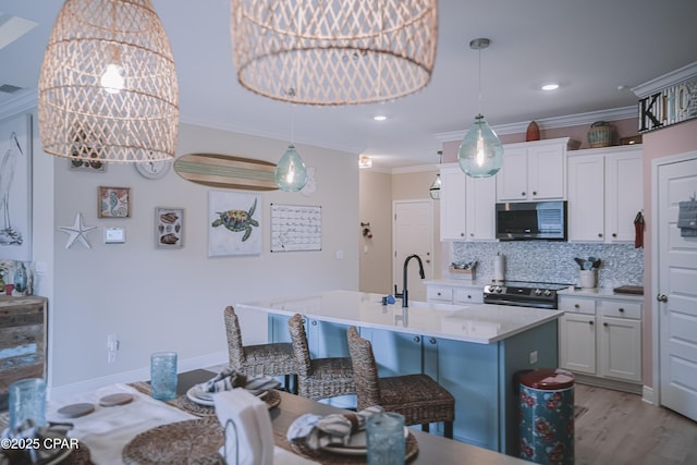 kitchen featuring tasteful backsplash, ornamental molding, stainless steel appliances, a sink, and white cabinets