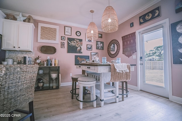 dining area featuring a healthy amount of sunlight, ornamental molding, and light wood-type flooring