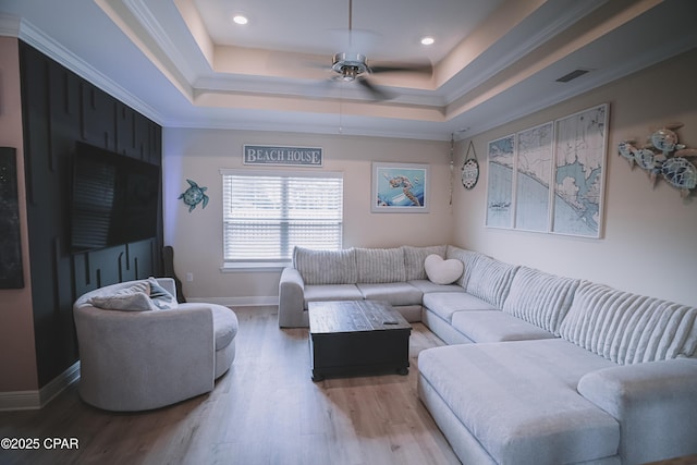 living room featuring wood-type flooring, crown molding, ceiling fan, and a tray ceiling