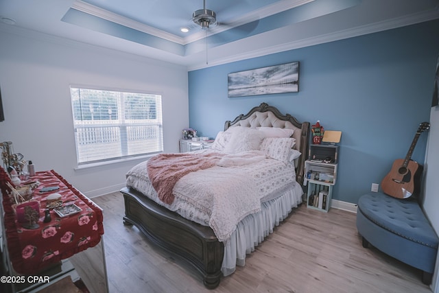 bedroom featuring crown molding, a tray ceiling, and light hardwood / wood-style flooring