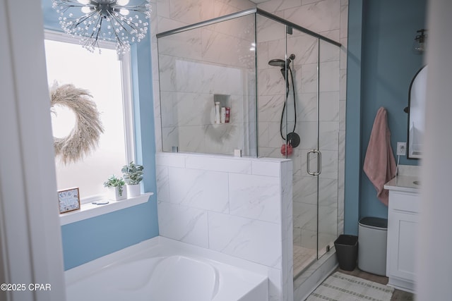 full bathroom with a shower stall, a garden tub, and an inviting chandelier