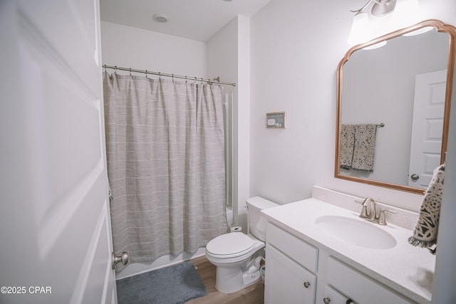 bathroom with wood finished floors, toilet, vanity, and shower / bath combo with shower curtain