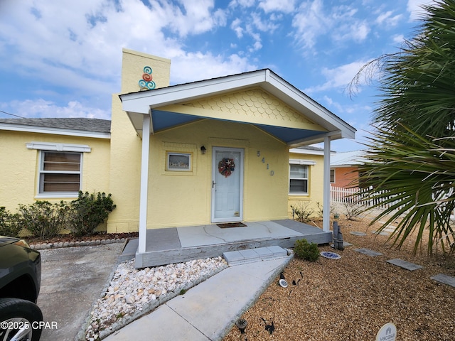 view of front of property featuring a shingled roof, fence, and stucco siding