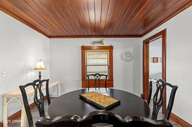 dining room featuring wooden ceiling, ornamental molding, wood finished floors, and a textured wall