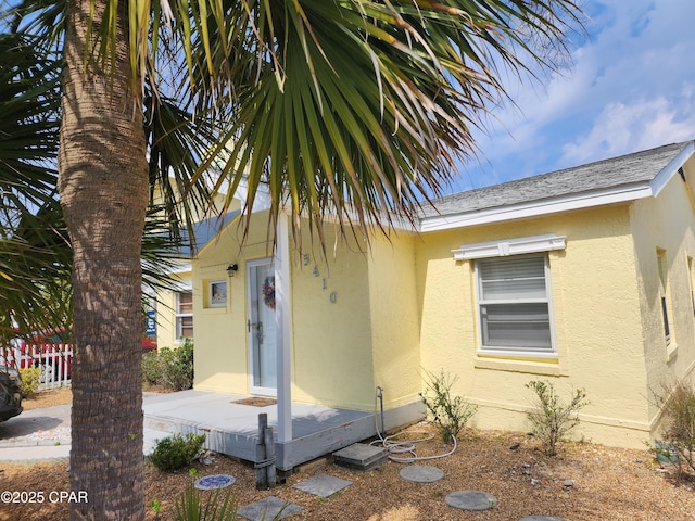 view of front of house featuring a shingled roof, fence, and stucco siding