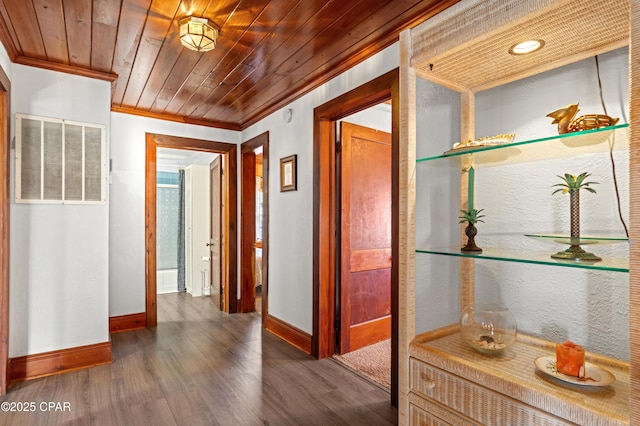 hall featuring wood finished floors, wood ceiling, visible vents, baseboards, and ornamental molding