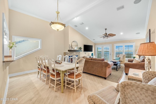 dining room featuring crown molding, a stone fireplace, lofted ceiling with beams, and light wood-type flooring