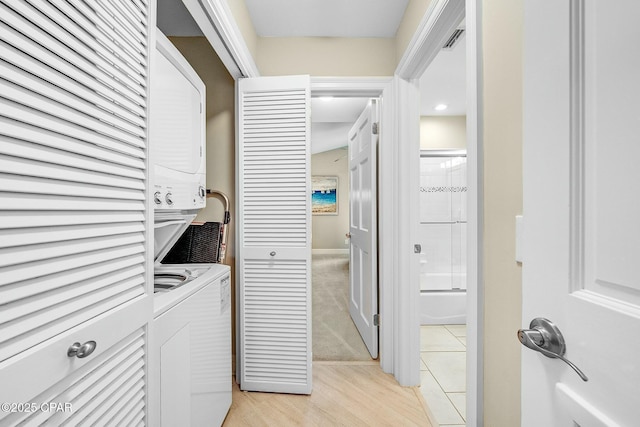 washroom with stacked washer / drying machine and light hardwood / wood-style floors