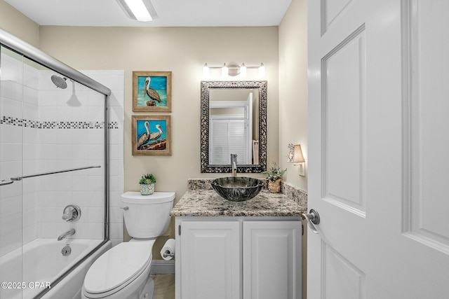 full bathroom with bath / shower combo with glass door, vanity, and toilet