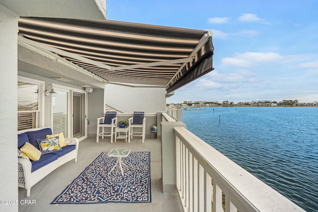 balcony with an outdoor living space and a water view