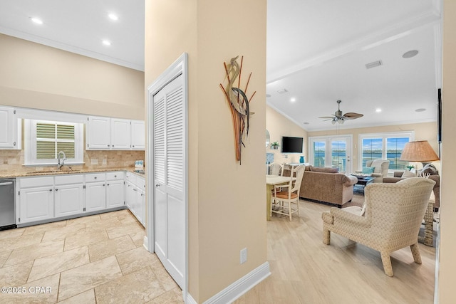 kitchen with sink, white cabinetry, ornamental molding, decorative backsplash, and vaulted ceiling