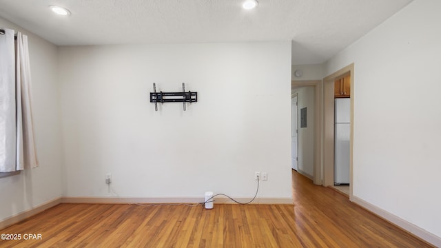 unfurnished dining area featuring a textured ceiling and light wood-type flooring