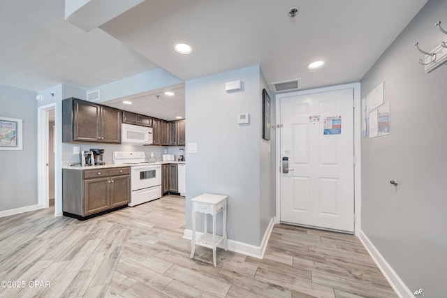 kitchen featuring dark brown cabinetry and white appliances