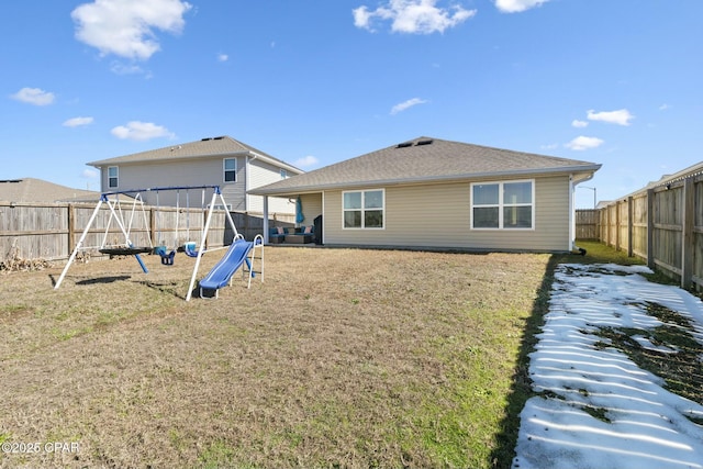 back of property with a yard and a playground