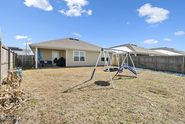 back of property featuring an outdoor living space, a lawn, and a playground