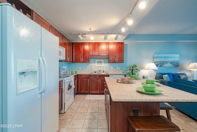 kitchen featuring sink, a center island, light tile patterned floors, a kitchen breakfast bar, and white appliances