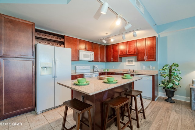 kitchen featuring a breakfast bar, sink, a center island, white appliances, and light hardwood / wood-style flooring