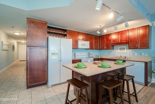 kitchen with sink, white appliances, a breakfast bar, and a center island