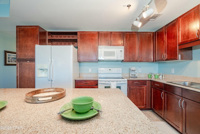 kitchen featuring sink, light stone counters, light tile patterned floors, track lighting, and white appliances